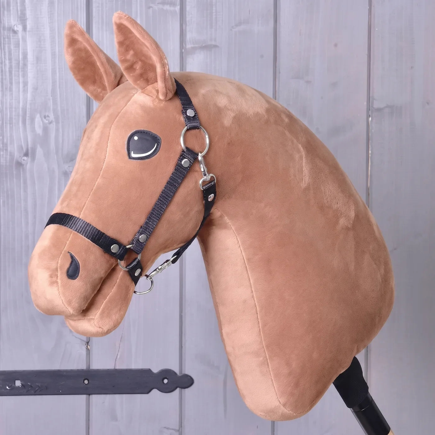 Costruisci il tuo cavallo di Hobby Horse LarDen: una testa di Hobby Horse in peluche con briglia, montata su un bastone, appoggiata a una parete di legno, ideale come ispirazione per creare il tuo cavallo unico con il configuratore “Build your horse” di Hobby Horse LarDen prima di completare l'acquisto.
