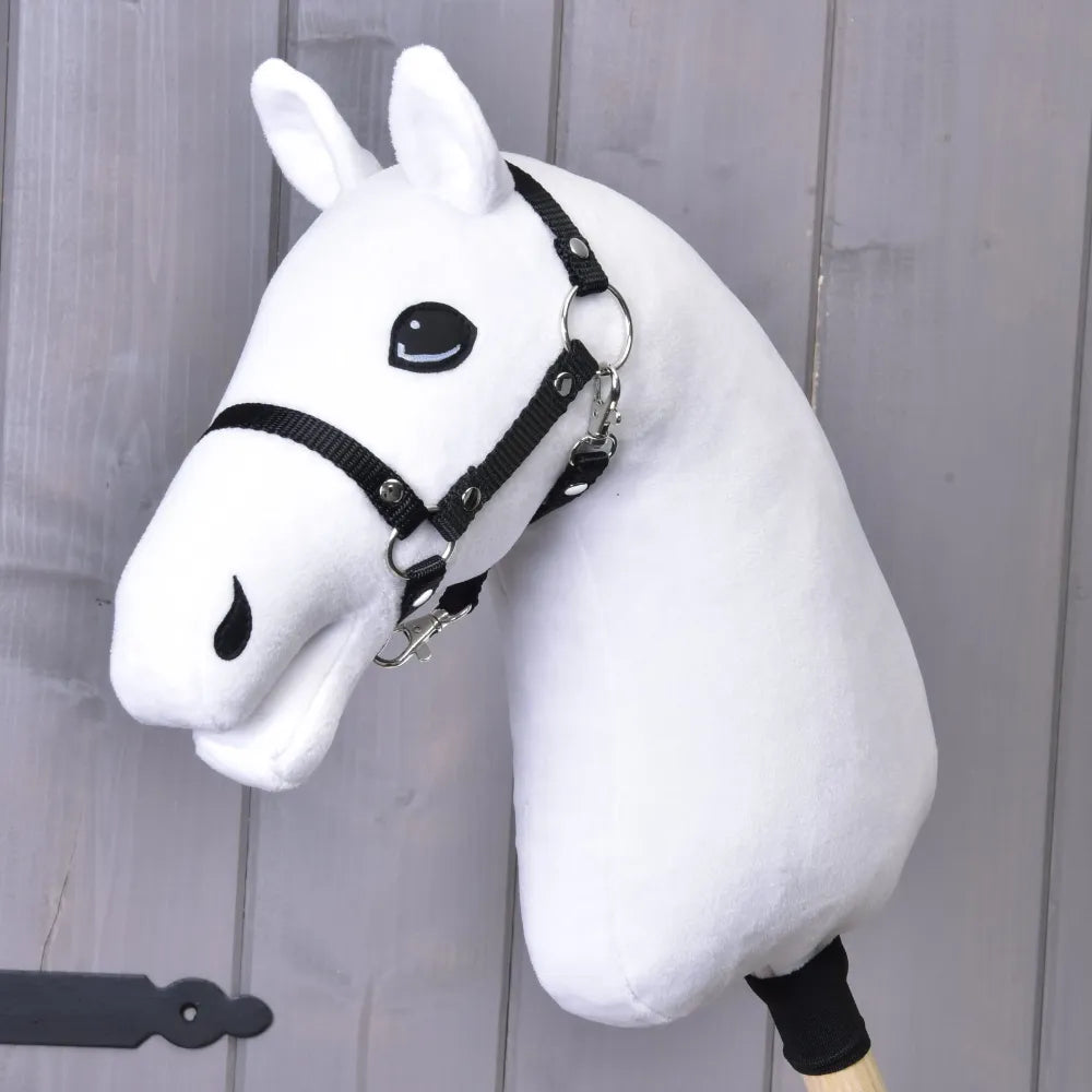 Costruisci il tuo cavallo di related_to_12441055625556 con Hobby Horse bianco, criniera in pelliccia sintetica tricolore e briglia nera, montato su un bastone di legno su uno sfondo di legno grigio chiaro.