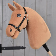 The “Build your horse” plush Chestnut Hobby Horse head by related_to_12441055625556 features a black bridle and reins, along with a striking brown & white mane. It is mounted on a stick and displayed against a gray wooden background.