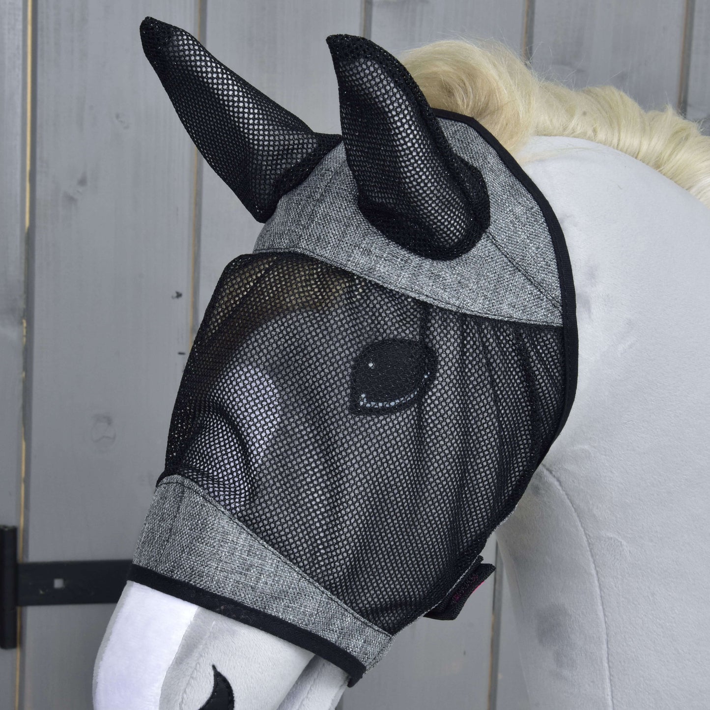 Manichino di cavallo bianco che indossa la Maschera Antizecche De Luxe Grigio Chiaro di Hobby Horse LarDen, che copre orecchie e occhi, davanti a uno sfondo in legno.